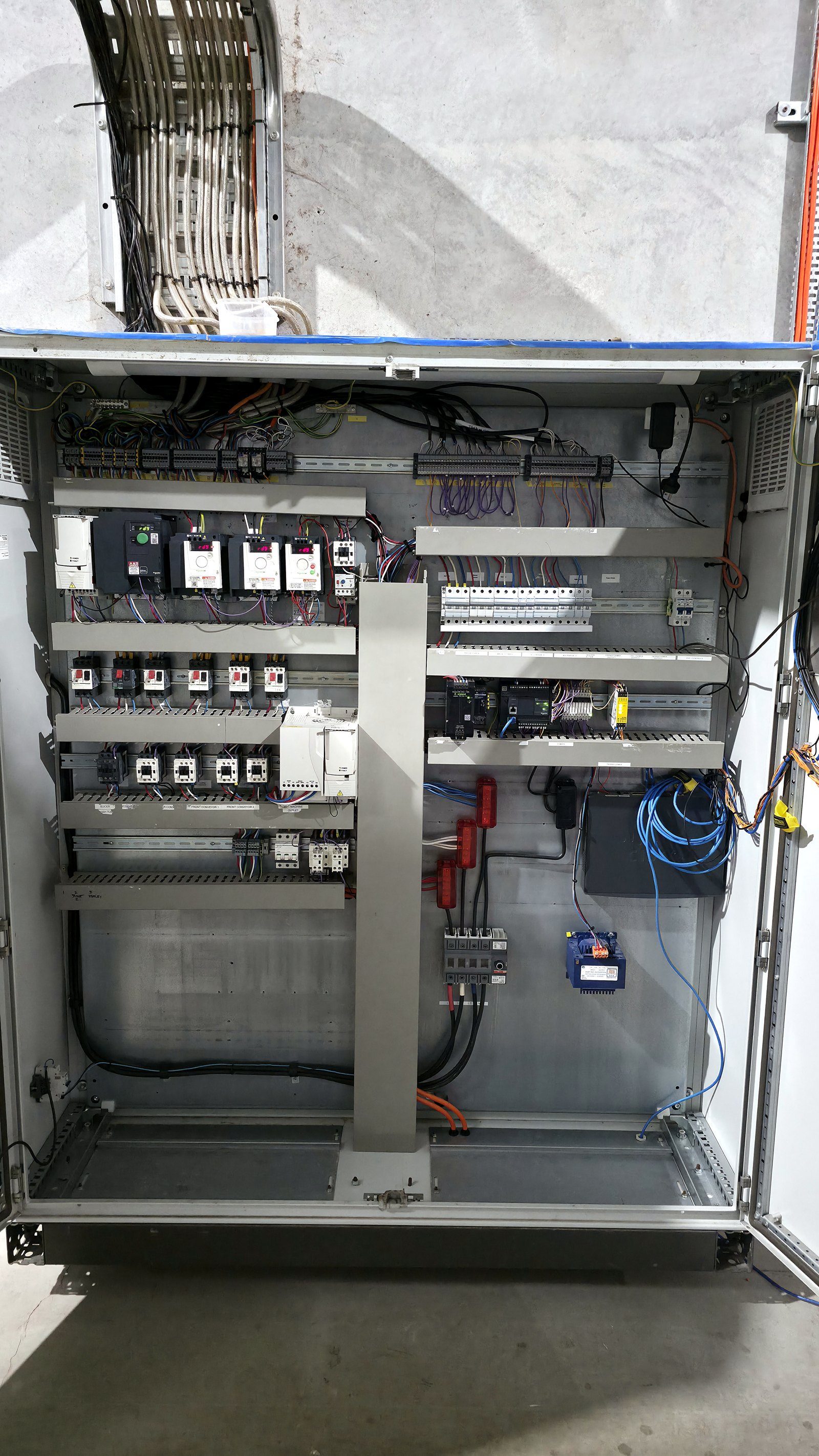 Inside the control cabinet — variable-speed drive fleet, PLC and neatly loomed DIN rails