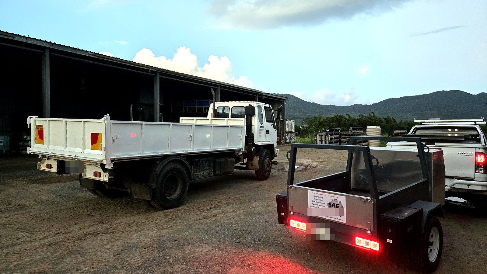 Finished 3-way tipper truck beside the SAE Engineering work trailer at dusk